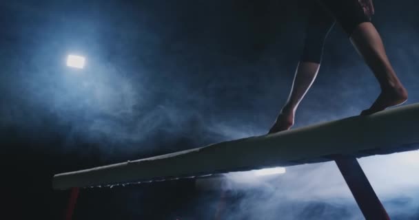 Primer plano del pie de una gimnasta profesional saltando en cámara lenta en el humo en una viga de equilibrio. Gimnasia para mujeres. Gracia y un estilo de vida saludable — Vídeos de Stock