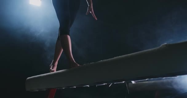 Ноги Профессиональные девушки гимнастки прыгать в замедленной съемке в дыму на балке баланса. Женская спортивная гимнастика — стоковое видео