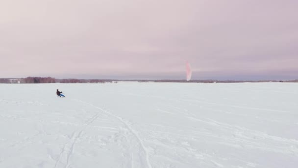 Kitesurfen in de winter op het snowboard of ski. Schaatsen op het ijs in de wind. Mooie gekleurde zeilen. — Stockvideo