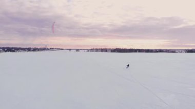 Yavaş hareket: Bir erkek atlet kayaklar üzerinde kiting devreye girer. Büyük bir göl buz üzerinde rulo. İnişli çıkışlı, çeşitli atlar, darbeler ve diğer çalışmaları gerçekleştirir. Rüzgarlı güneşli kış günü