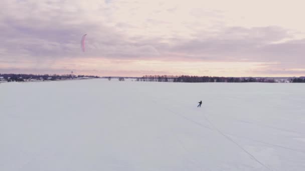 Slow Motion: Een mannelijke atleet is betrokken bij het vliegeren op ski's. Hij rolt op het ijs van een groot meer. Rollen, voert hij verschillende sprongen, staatsgrepen en andere oefeningen. Winderige en zonnige winterdag — Stockvideo