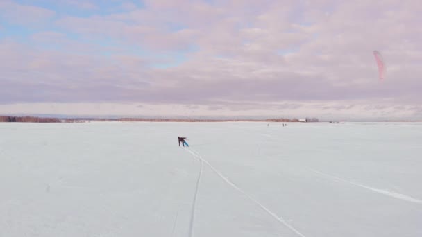 Kite surfer wordt getrokken door zijn kite over de sneeuw — Stockvideo