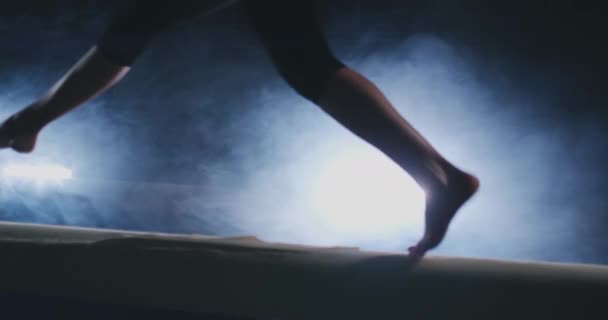 Nahaufnahme des Fußes eines professionellen Turnermädchens, das in Zeitlupe auf einem Balken im Rauch springt. Frauenturnen. Anmut und ein gesunder Lebensstil — Stockvideo