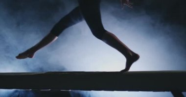 Bacaklar profesyonel kız jimnastikçiler duman yavaş çekimde denge denge aletinin üstüne atla. Bayan Artistik Jimnastik