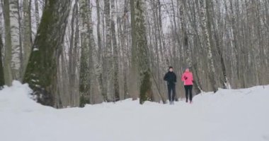 Erkek ve kadın kış yavaş çekimde parkta koşmak