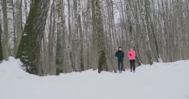 Uomo e donna corrono nel parco in inverno al rallentatore — Video Stock