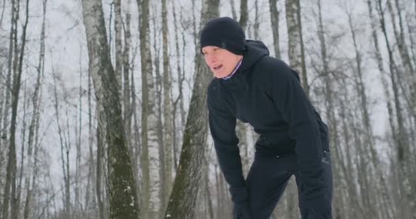 En ung man på en morgon jogga vintertid skogen var trött och stannade för att fånga hans andedräkt. Han återhämtade sig sin styrka och övervann trötthet och fortsatte att springa. Uthållighet och övervinna svaghet — Stockvideo