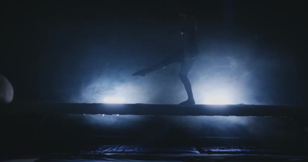 Mujer Gimnasia Artística. En cámara lenta en el humo, la chica realiza elementos complejos del programa olímpico en una viga de equilibrio . — Vídeos de Stock