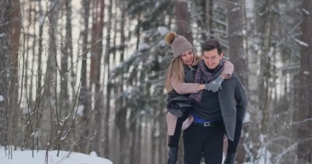 Jonge mooie paar nemen plezier en lacht buiten in de besneeuwde winter — Stockvideo