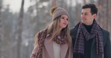 Genç evli çift Kış ormanda yürüyüş seviyorum. Bir erkek ve bir kadın birbirlerini gülüyor ve ağır çekimde gülümseyerek bak. Sevgililer günü aşk hikayesi.