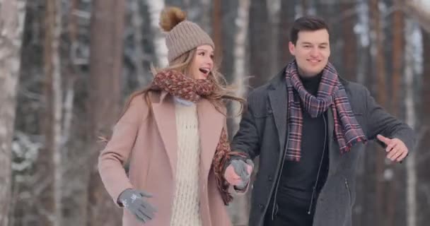 Młode małżeństwo w miłości spaceru w lesie zimą. Mężczyzna i kobieta spojrzeć na siebie, śmiech i uśmiech w zwolnionym tempie. Historia miłości Walentynki. — Wideo stockowe