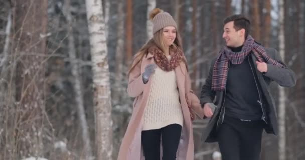 Νεαρό παντρεμένο ζευγάρι βόλτες μέσα στο δάσος του χειμώνα. Ένας άνδρας και μια γυναίκα που φαίνονται σε κάθε άλλο γέλιο και το χαμόγελο σε αργή κίνηση. — Αρχείο Βίντεο