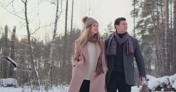 Casal jovem caminha pela floresta de inverno. Um homem e uma mulher olham um para o outro rindo e sorrindo em câmera lenta . — Vídeo de Stock