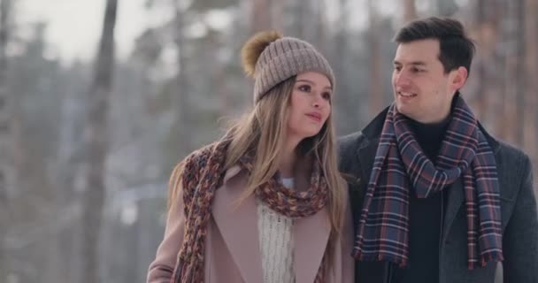 Jong getrouwd paar verliefd wandelen in de winter woud. Een man en een vrouw kijken elkaar lachen en glimlachen in slow motion. Valentijnsdag liefdesverhaal. — Stockvideo