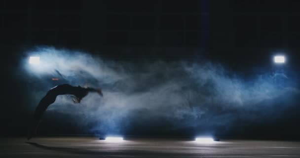 У повільному русі в диму дівчина акробат виконує кілька задніх перегонів і переворотів в повітрі . — стокове відео