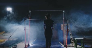 Duman kız ağır çekimde acrobat çubuk üzerinde döndürme ve bir darbe ile atlama yapar. Jimnastik yarışmaları.