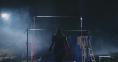 Duman kız ağır çekimde acrobat çubuk üzerinde döndürme ve bir darbe ile atlama yapar. Jimnastik yarışmaları.