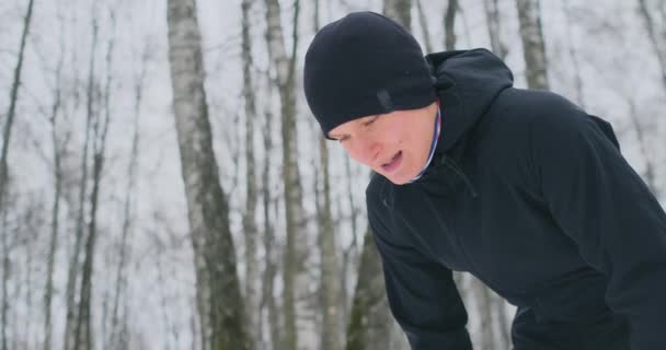 Mladý muž na ráno běhat v zimě lese byl unavený a zastavila k odpočinku a běžel dál. Jeho sílu a přemohla únava a nadále provozovat. Vytrvalost a překonání slabosti — Stock video