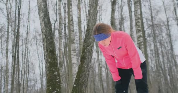 Молода жінка на ранковому бігу в зимовому лісі втомилася і перестала відпочивати і бігати далі. Він відновив свою силу і подолав втому і продовжував бігати. Постійність і подолання слабкості — стокове відео