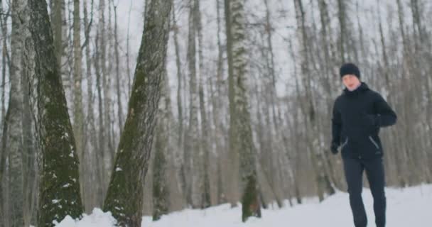 En ung man på en morgonjogg i skogen vintern var trött och stannade för att vila och körde på. Han återhämtade sig sin styrka och övervann trötthet och fortsatte att springa. Uthållighet och övervinna svaghet — Stockvideo