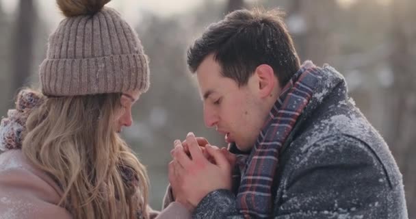 Un homme attentionné réchauffe ses femmes en hiver dans la rue dans un parc enneigé . — Video