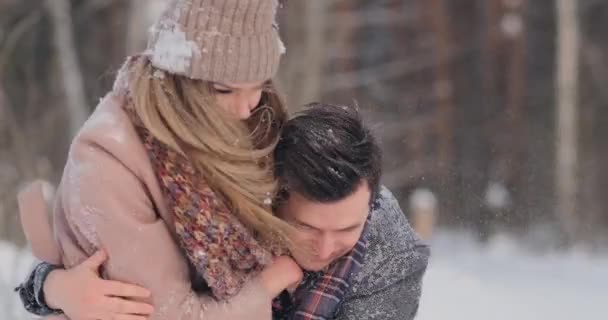 Pareja feliz está jugando juego de invierno afuera disfrutando de la luz del sol y el clima cálido de invierno en las montañas. fuerte chico es llevar novia en su hombros y giros su — Vídeos de Stock