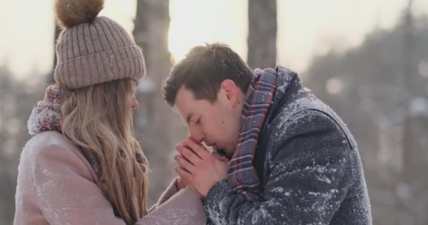 Ένα ζευγάρι στην αγάπη ένας άνθρωπος ζεσταίνει τα χέρια του με την αναπνοή του μια γυναίκα. Κομψό ζευγάρι στο πάρκο το χειμώνα για μια βόλτα. — Αρχείο Βίντεο