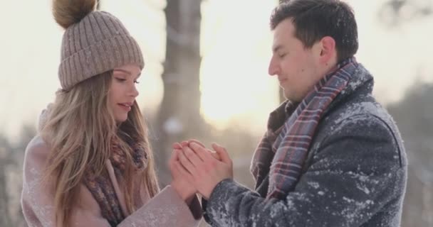 Um casal apaixonado um homem aquece as mãos com o seu hálito uma mulher. Casal elegante no Parque no inverno para um passeio . — Vídeo de Stock