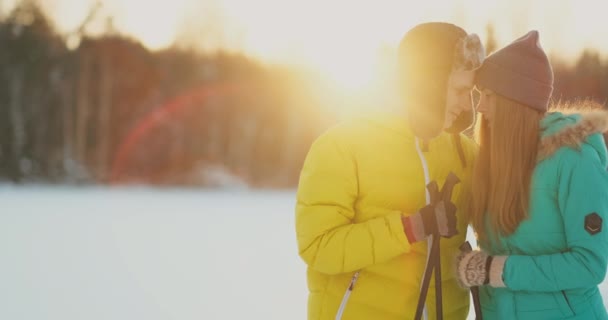 Μέσα στο δάσος του χειμώνα στο ηλιοβασίλεμα αγαπώντας ζευγάρι σκι και να κοιτάξουμε γύρω από την ομορφιά της φύσης και Αξιοθέατα σε αργή κίνηση. — Αρχείο Βίντεο