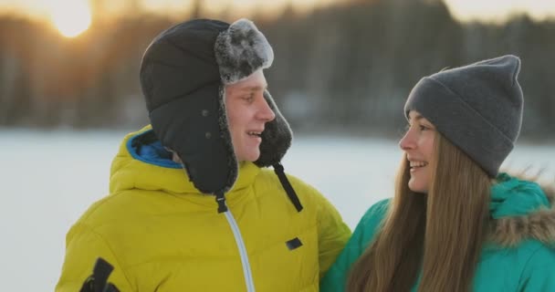 Człowiek w żółtą kurtkę i dziewczyna w Niebieski kombinezon, jazda na nartach w zwolnionym tempie o zachodzie słońca — Wideo stockowe
