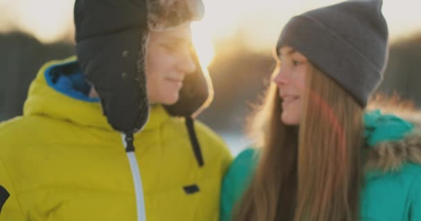 In the winter forest at sunset loving couple skiing and look around at the beauty of nature and attractions in slow motion. — Stock Video