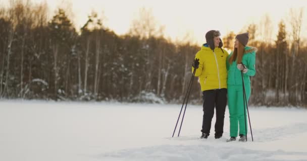 冬の森でスキーをしながら愛情のこもった目でお互いを見てください。結婚されていたカップルは健康的なライフ スタイルを実践します。 — ストック動画