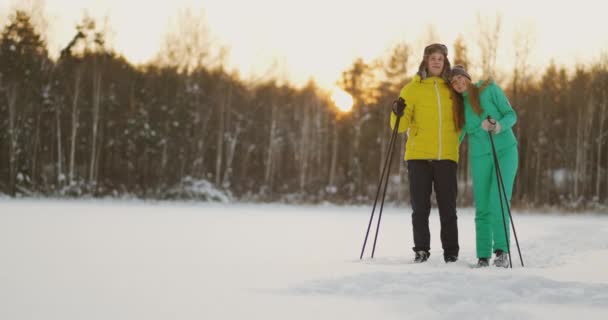 En man omfamnar en kvinna som står i skogen vid solnedgången efter en vinter promenad på skidor. St Alla hjärtans dag. Romantik och varma känslor av älskare. Slow motion — Stockvideo