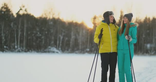 I skogen vintern på sunset älskande par skidåkning och titta på vackra natur och sevärdheter i slow motion. — Stockvideo