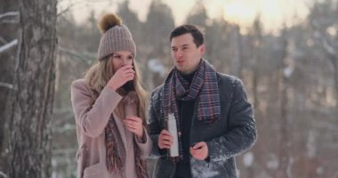 Güzel ve şık bir çift erkek ve kadın hipsters Paltonu ve kaşkolünü içinde bir yürüyüşten sonra bir termos kış orman içinde gelen çay iç. Aşk hikayesi