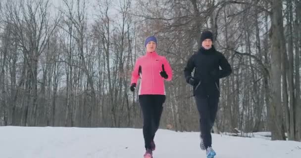 Positiv vackra unga friska par kör med sportkläder genom skogen på vintern morgonen — Stockvideo