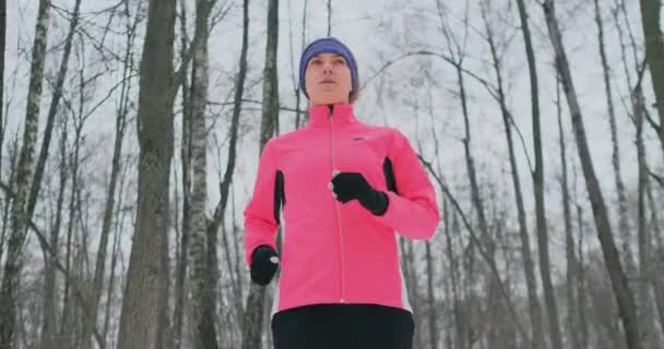 Женщина, бегущая в снежную зиму под солнцем . — стоковое видео