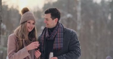 Güzel ve şık bir çift erkek ve kadın hipsters Paltonu ve kaşkolünü içinde bir yürüyüşten sonra bir termos kış orman içinde gelen çay iç. Aşk hikayesi