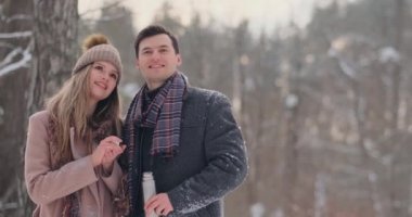 Mutlu çift sıcak çay bardak kış peyzaj üzerinde tutarak. Bir ağacın ayakta ve sıcak fincan çay içme kış tatil, aşık genç çift