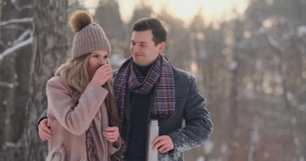 Kochający Para mężczyzna i kobieta w zimie lasu picia herbaty z termos. Stylowy mężczyzna i kobieta w płaszcz w Park zimą na spacer. Zwolnionym tempie — Wideo stockowe