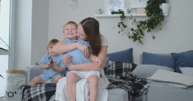 Diwanie üzerinde oturan bir elbise içinde sevgi dolu bir anne oğlu ve öpücük sarılarak. Mutlu aile armoni ve anlama