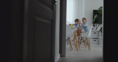 Mutlu aile genç güzel anne ve iki oğlu ile renkli kalemler mutfakta masada oturan çizin. Kamera ağır çekimde hareket eder.