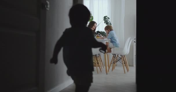 Η μαμά βοηθά γιους μάθετε να επιστήσει την κάνει εργασία προσχολική προετοιμασία στο σπίτι κάθεται στην λευκή κουζίνα. Δύο αδέλφια συγκεντρώσει ένα πορτρέτο του μαμά — Αρχείο Βίντεο