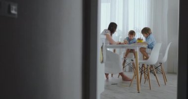 Çocuklardan iki çocuk annesi mutfakta oturuyor ile çekmek.