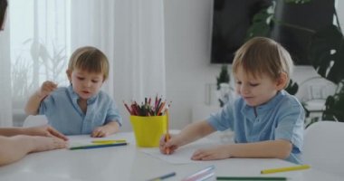 Annem ve onun iki oğlu renkli kalemler aile çimenlerin üzerine yaz aylarında çizim mutfak masasında oturuyor. Çocuklar öğrenmek çizmek ve anne çizim ile yardımcı olur.