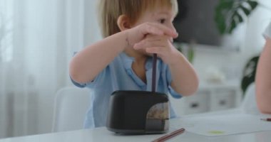 Mutfak masada oturan bir kalemtıraş içinde renkli kalem keskinleştirmek çocuk