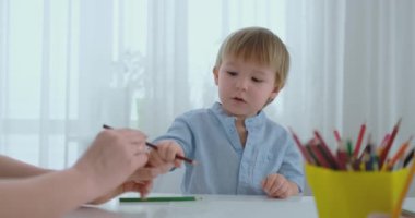 Mutfakta masada oturan mavi tişört bir çocukta bir işareti çizer