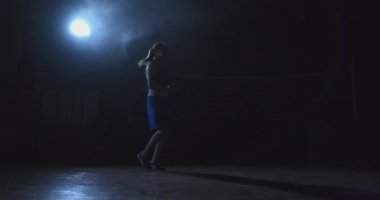 Spor salonu boks jimnastik salonu bir yüzük ve güzel bir genç kadın şort ve tişört ip atlama ile genel planı.