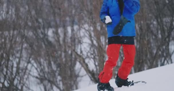 Сноубордист кидає сніжку в камеру, що стоїть на лижному схилі — стокове відео
