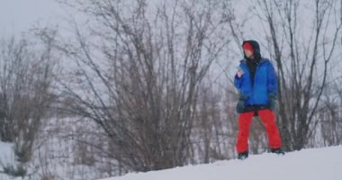 Yavaş çekim bir kayak pisti üzerinde sürüş sırasında bir smartphone kullanarak bir snowboarder